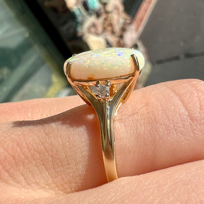 A ladies' yellow gold ring set with two diamonds and an oval cut natural opal stone.