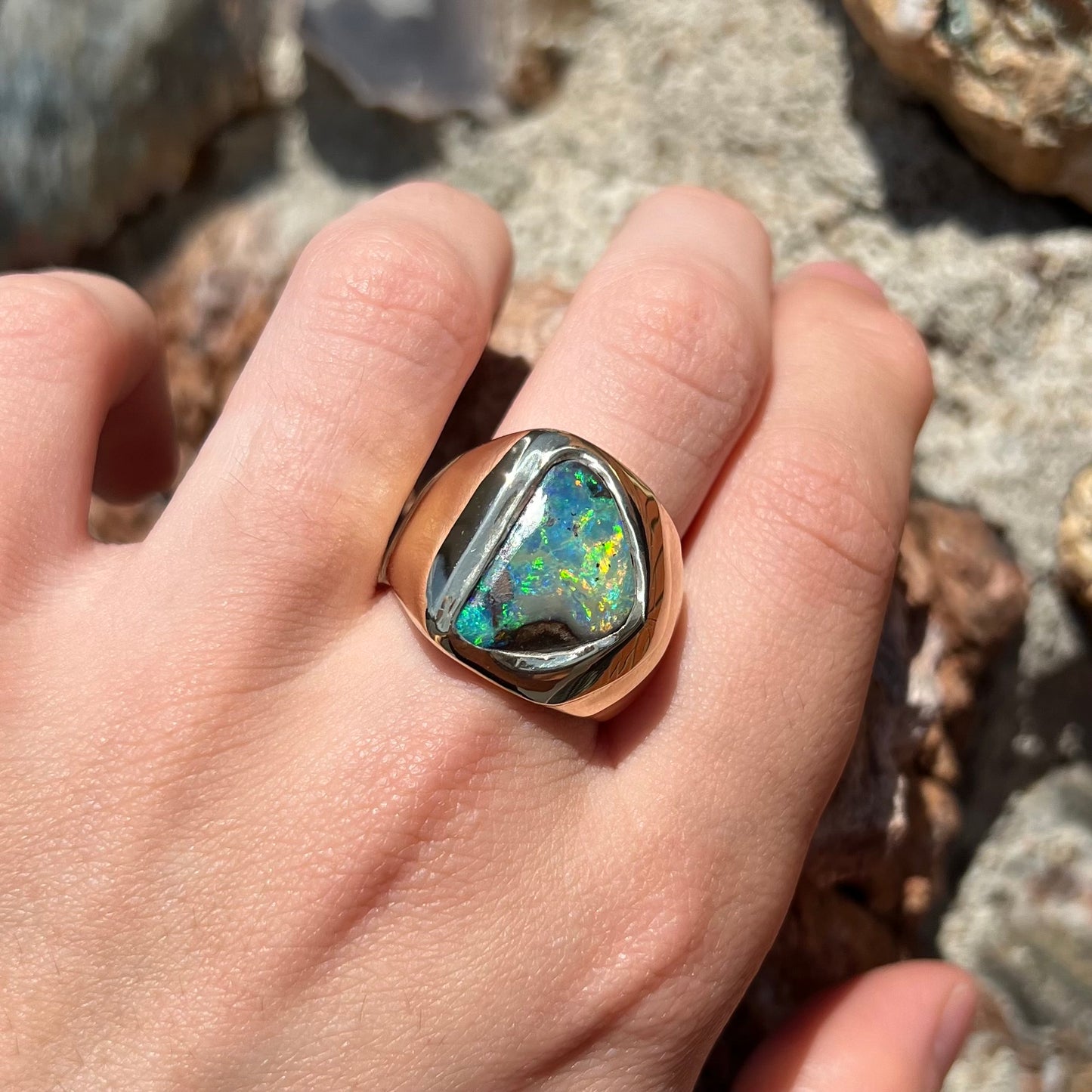 A men's yellow gold solitaire ring set with a triangular shaped natural boulder opal.