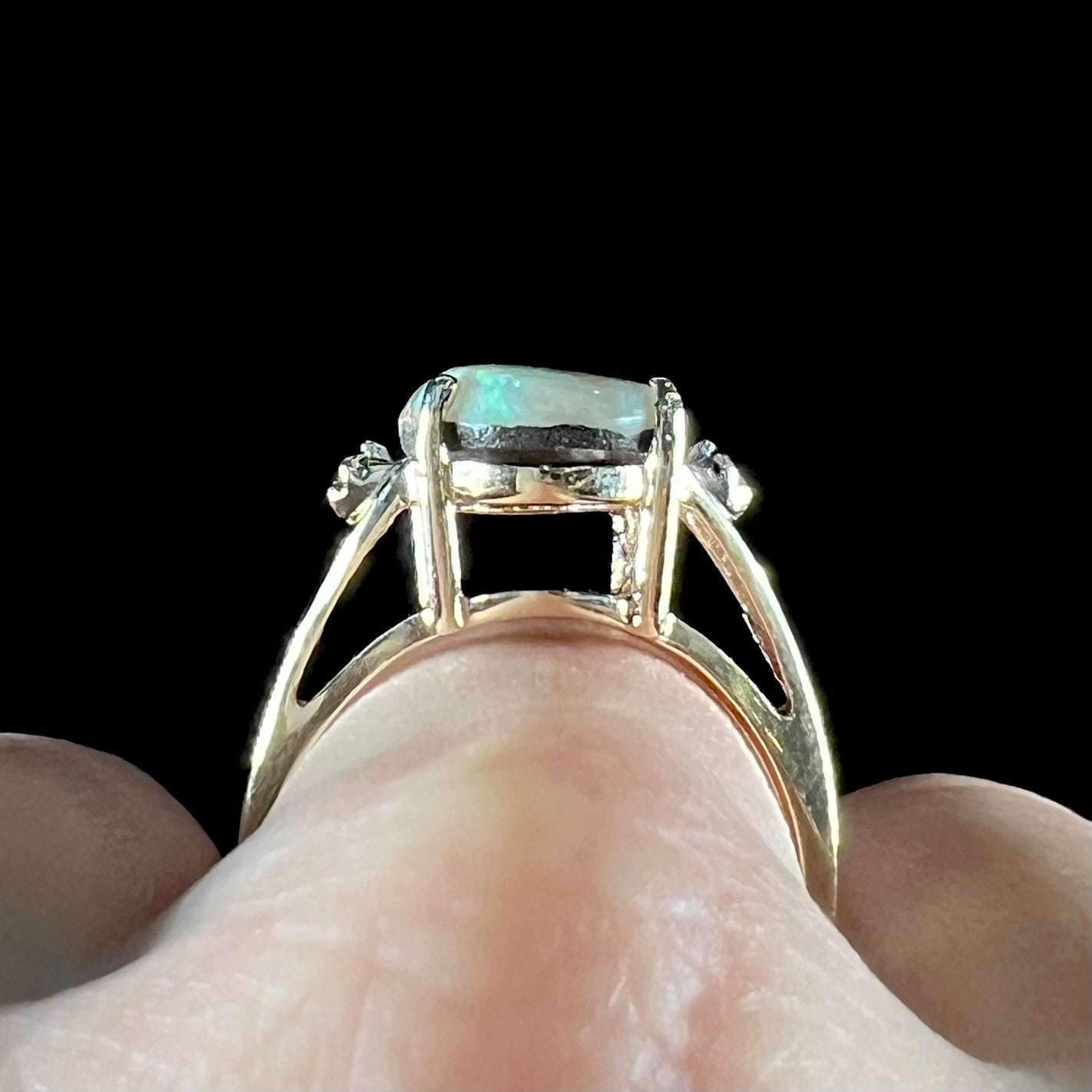 A ladies' Australian boulder opal ring set in yellow gold with diamond accents.  The opal shimmers green and pink and has fissure inclusions.