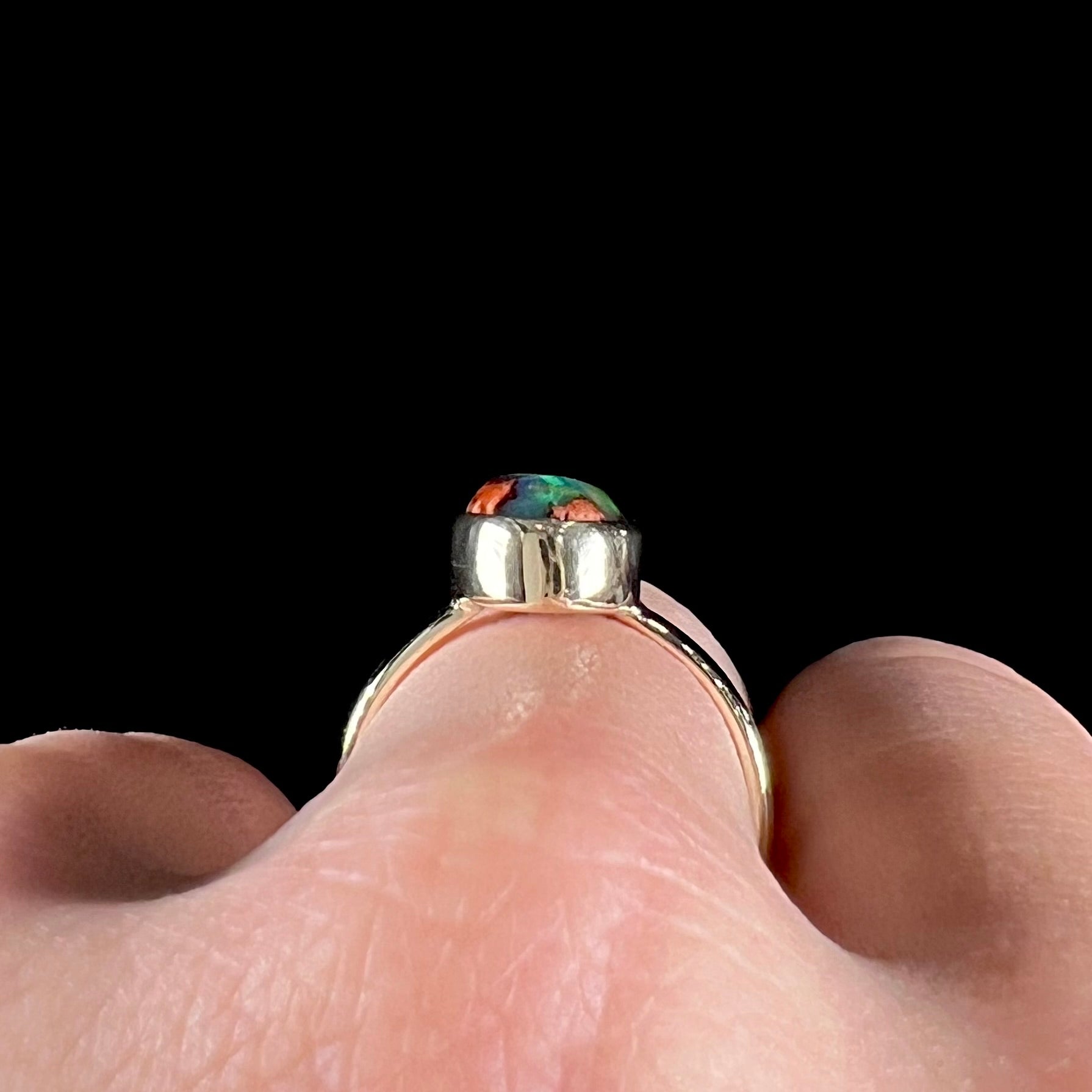 A ladies' yellow gold solitaire ring bezel set with an oval cabochon cut natural black Mexican cantera fire opal stone.