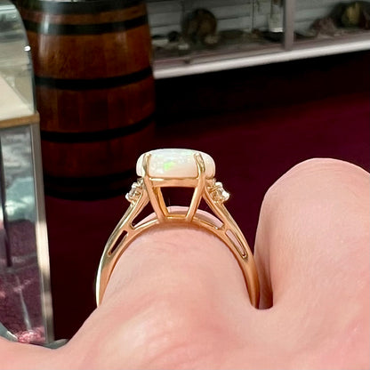A ladies' yellow gold ring set with two diamonds and an oval cut natural opal stone.