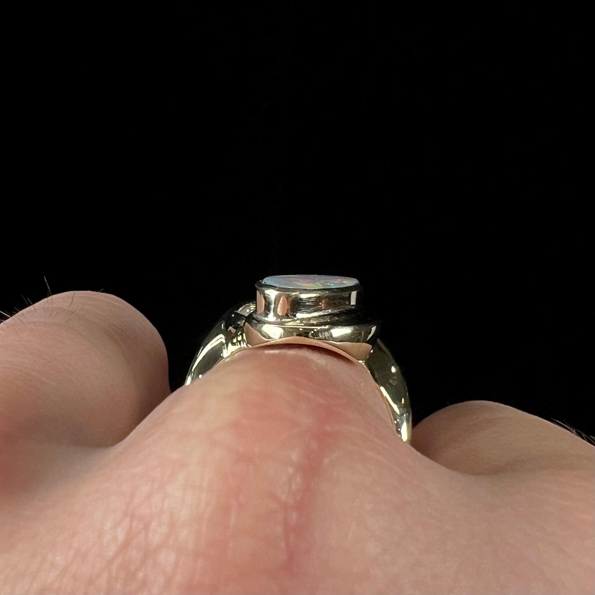 A ladies' yellow gold, bezel set ring mounted with a natural 1.15 carat black opal and round diamond.