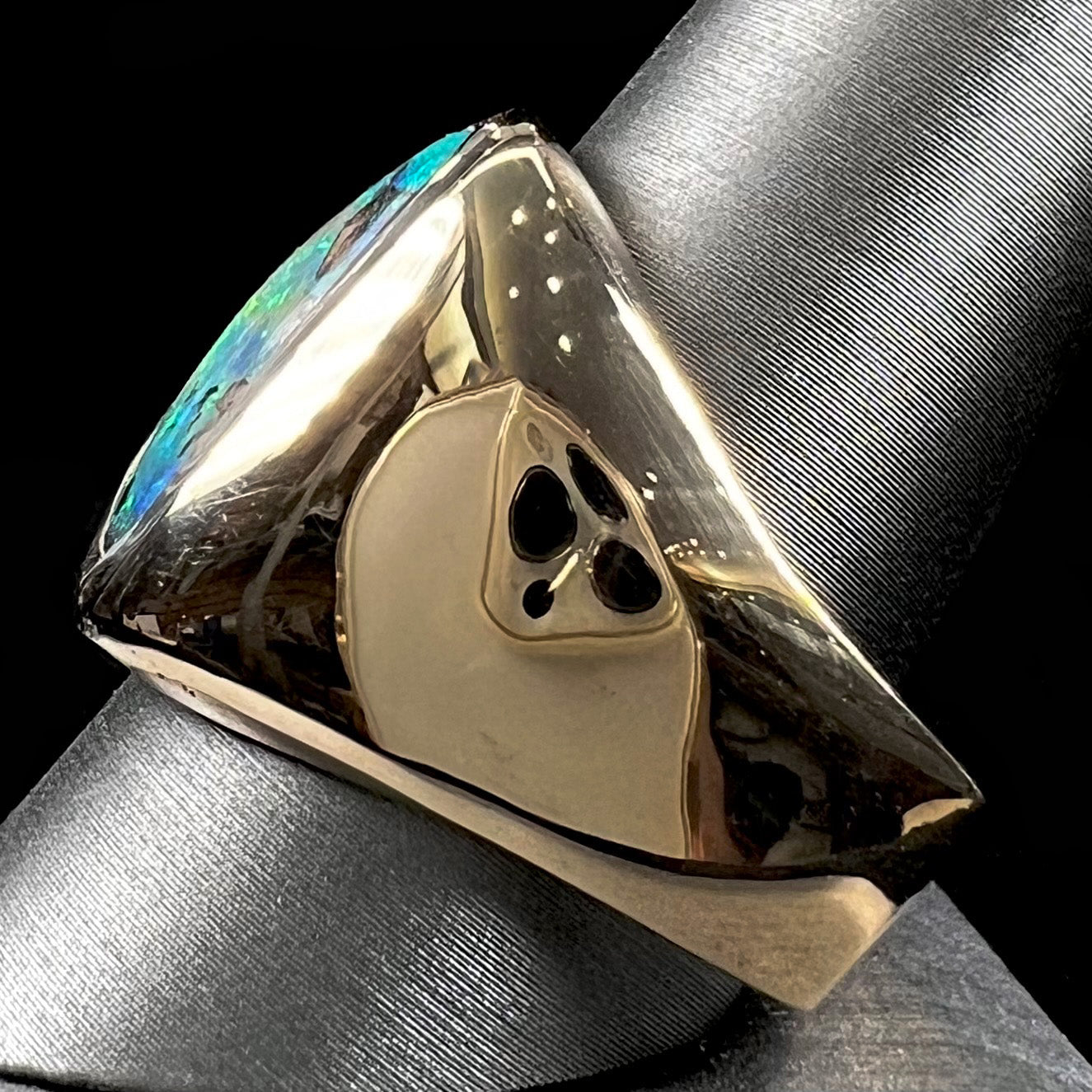 A men's yellow gold solitaire ring set with a triangular shaped natural boulder opal.