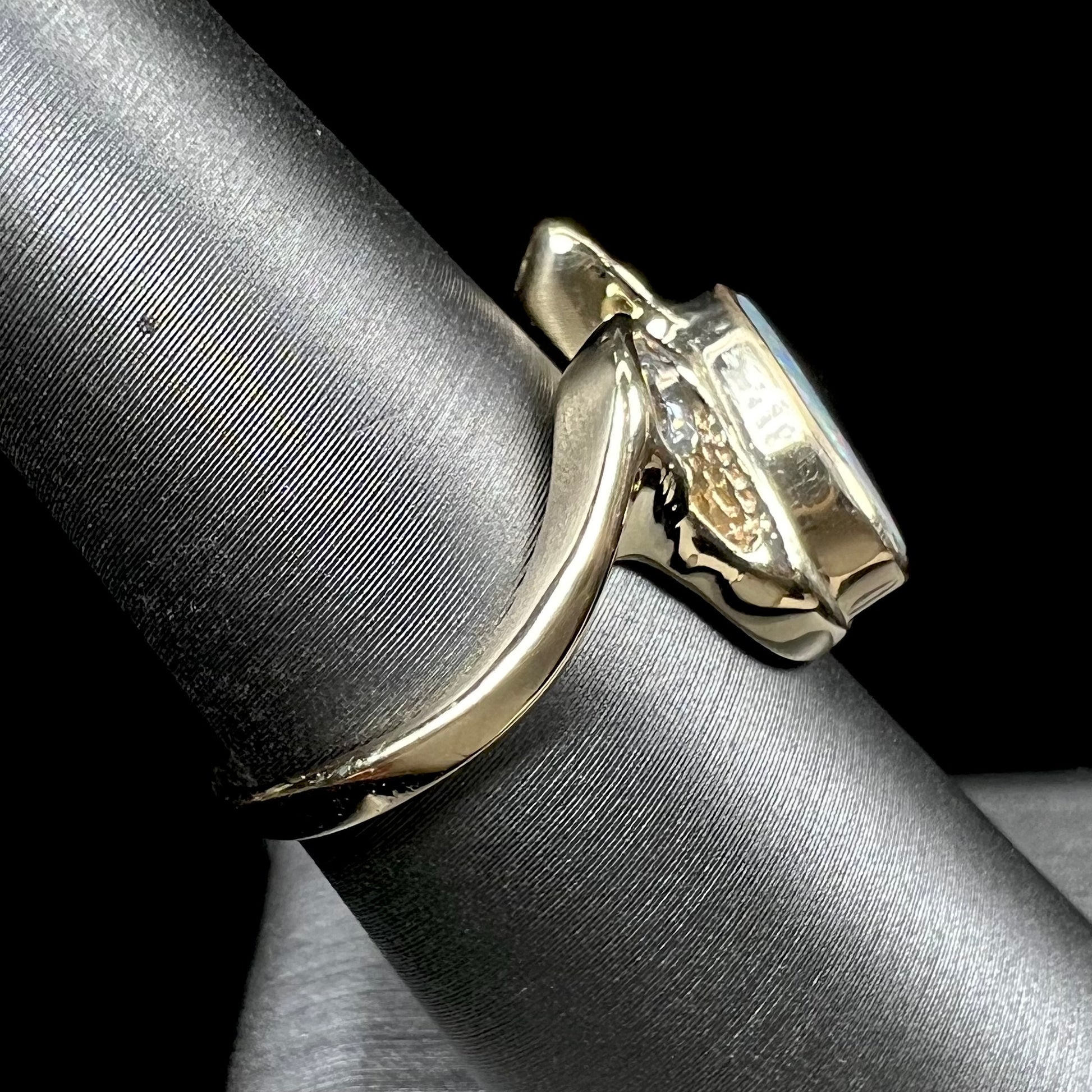 A ladies' yellow gold, bezel set ring mounted with a natural 1.15 carat black opal and round diamond.
