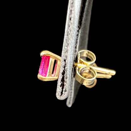 A pair of yellow gold stud earrings set with pinkish red Burmese rubies.  The rubies are emerald cut.