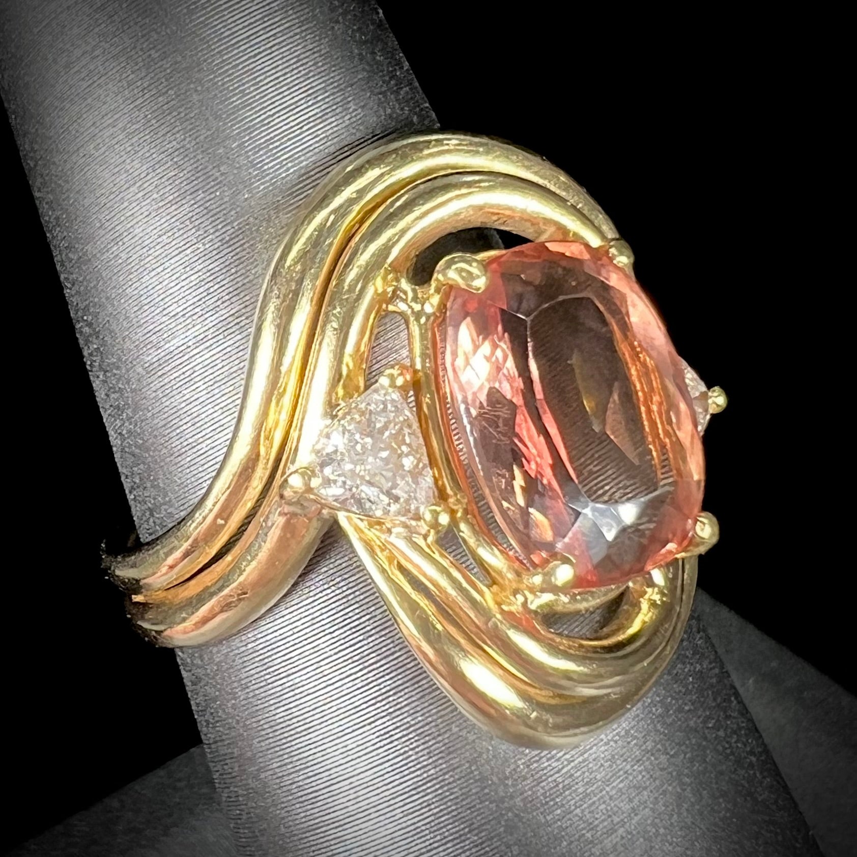 An 18 karat yellow gold ring set with two triangle cut diamonds and a cushion cut imperial topaz.