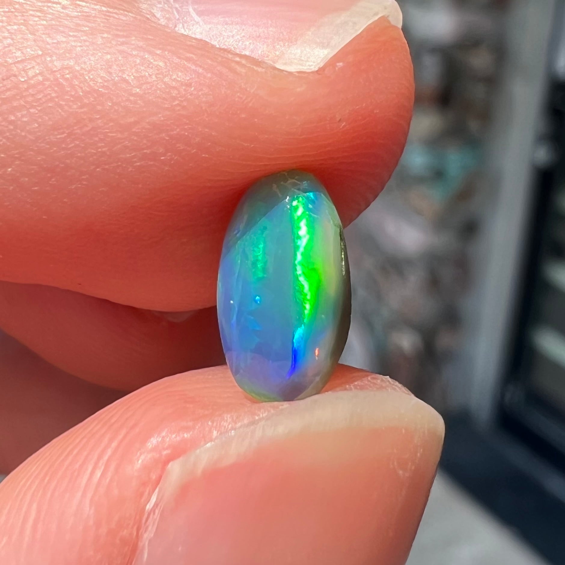 A loose, pill shaped black opal stone from Lightning Ridge, Australia.  The opal is green and blue.