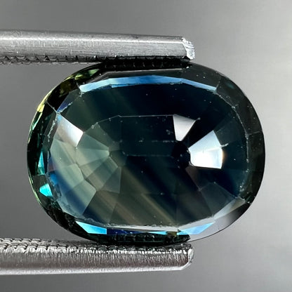 A loose faceted oval cut natural sapphire.  The stone is blue-green color.