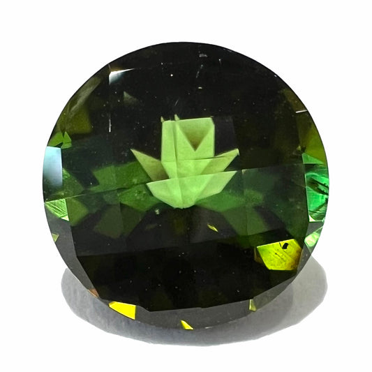A loose, round checkerboard cut green tourmaline stone with flashes of yellow.  The gem weighs 2.78 carats.