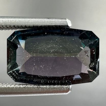 A loose, modified emerald cut, natural color change sapphire stone.  The stone shifts from black to blue to purple to green.