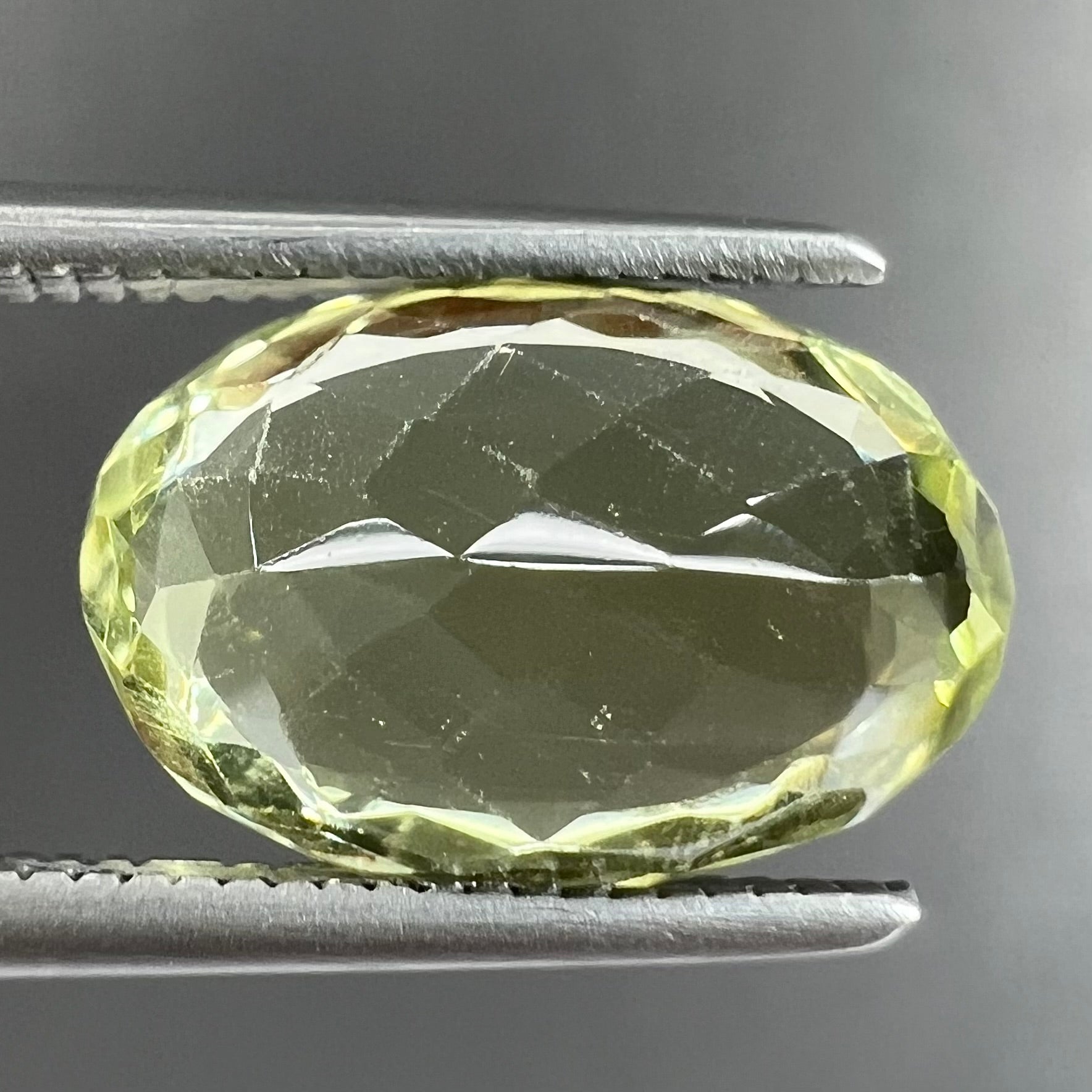 A loose, faceted oval cut chrysoberyl gemstone.  The stone is a greenish yellow color.