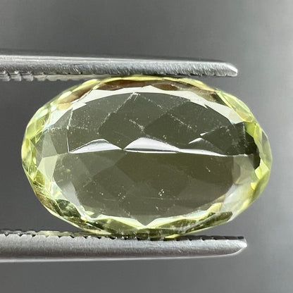A loose, faceted oval cut chrysoberyl gemstone.  The stone is a greenish yellow color.