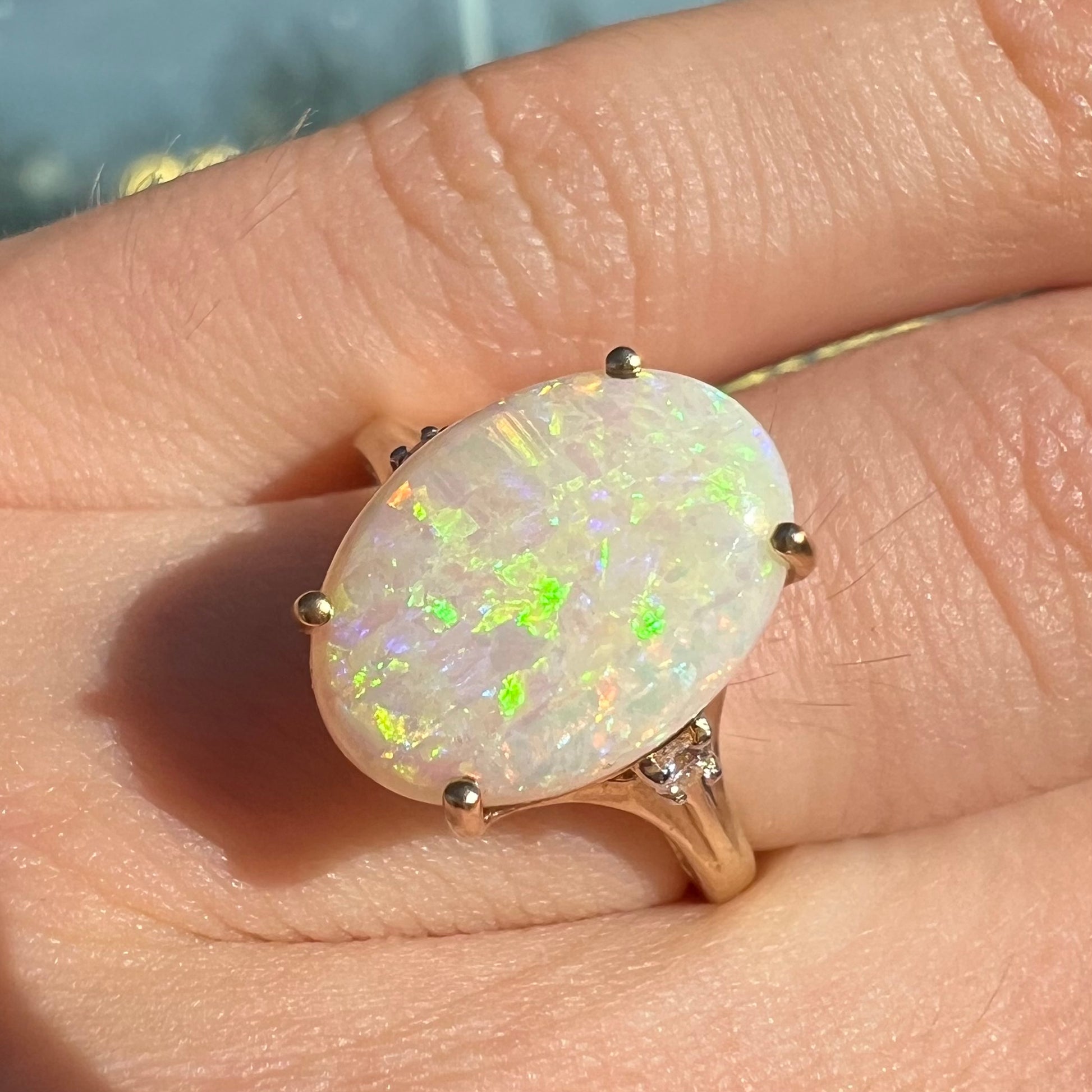 A ladies' yellow gold ring set with two diamonds and an oval cut natural opal stone.