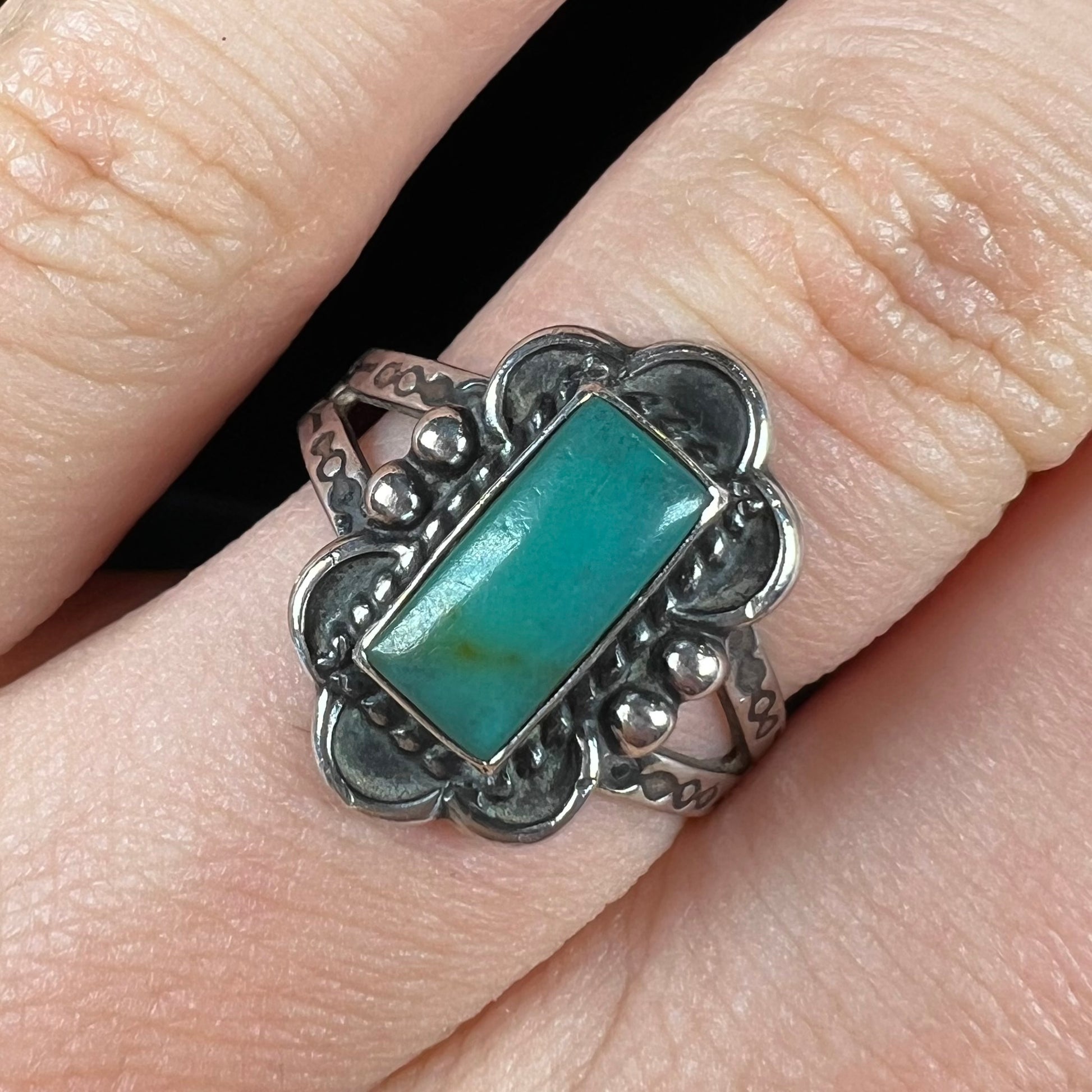 A ladies' silver ring stamped with Southwest style designs and set with a rectangular cabochon cut Royston turquoise stone.