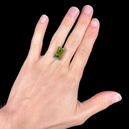 A rectangular step-cut yellowish green tourmaline gemstone.