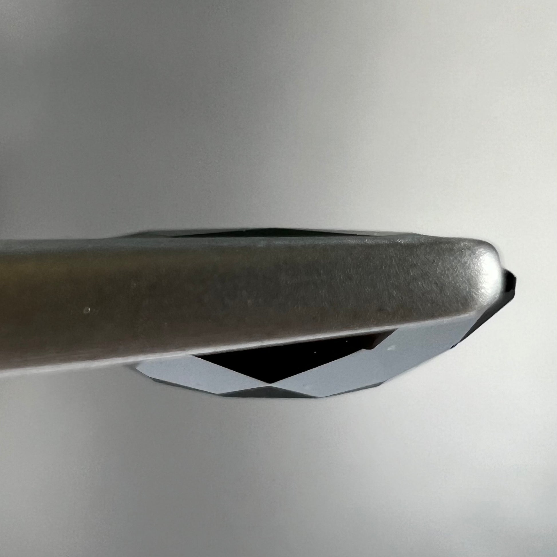 A faceted oval cut chrome tourmaline gemstone.  The stone is dark green.