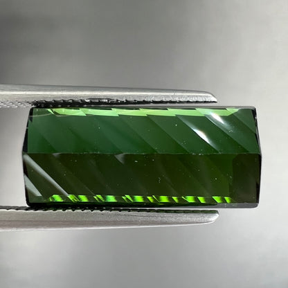A loose, rectangular laser cut green tourmaline gemstone.