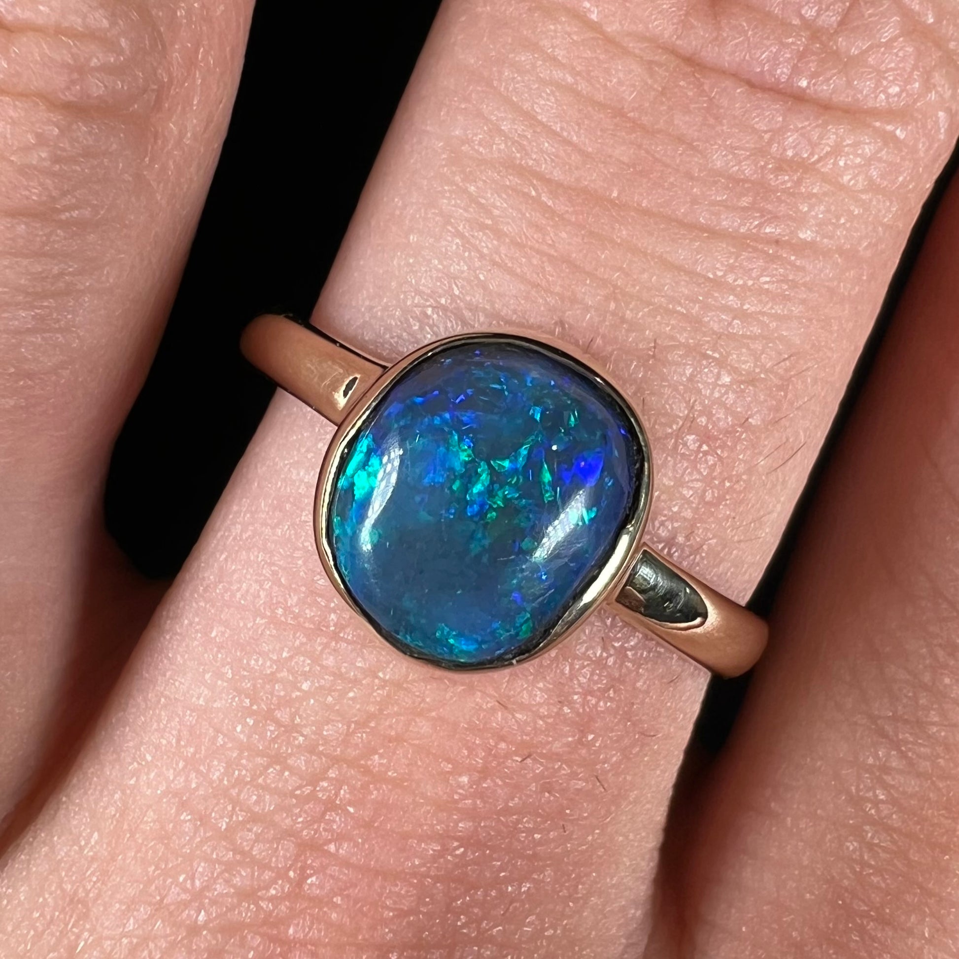 A ladies' natural black crystal opal solitaire ring handmade in 14 karat yellow gold.