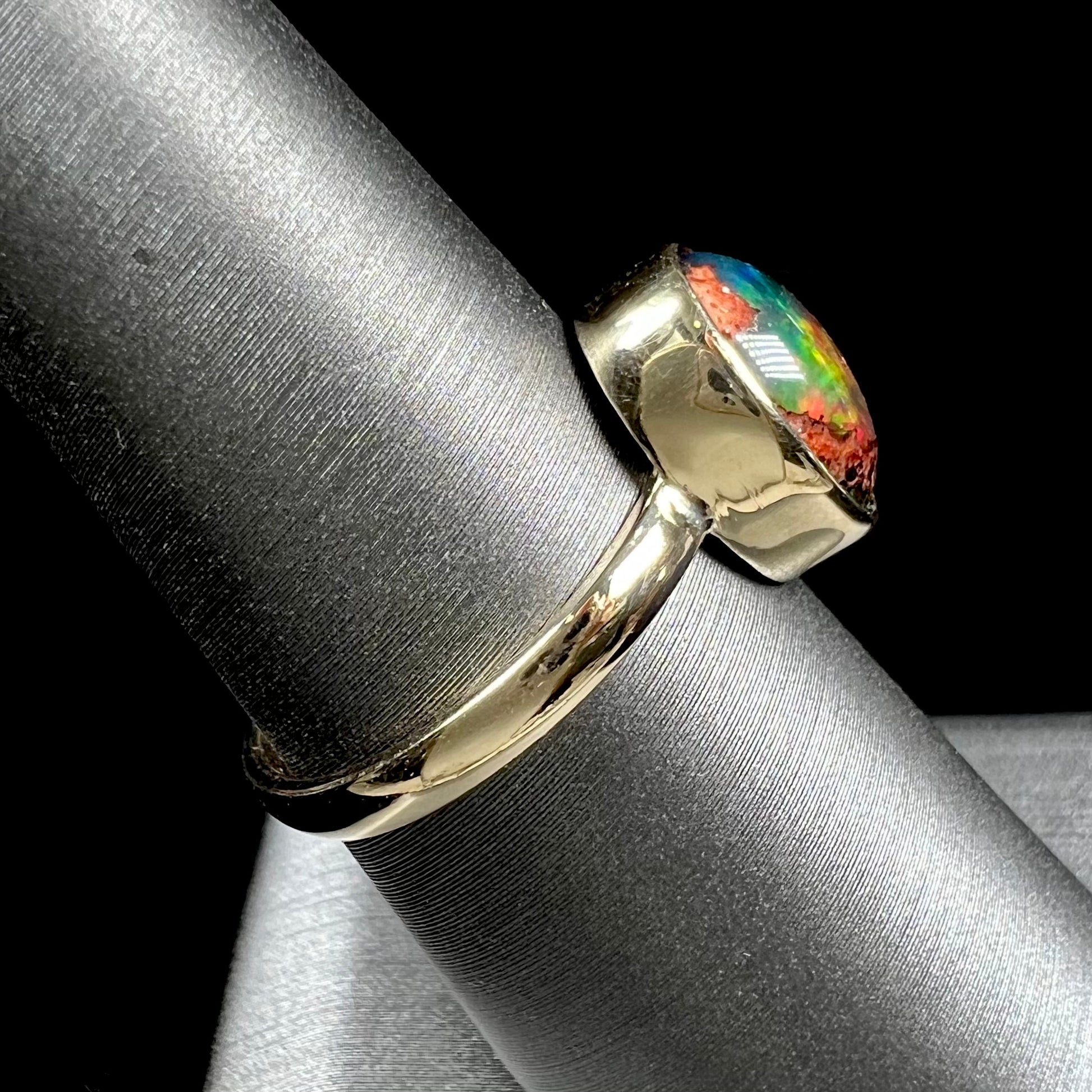 A ladies' yellow gold solitaire ring bezel set with an oval cabochon cut natural black Mexican cantera fire opal stone.
