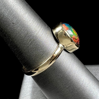 A ladies' yellow gold solitaire ring bezel set with an oval cabochon cut natural black Mexican cantera fire opal stone.