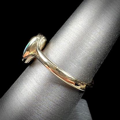 A ladies' oval cut black crystal opal solitaire ring handmade with a single split shank in yellow gold.