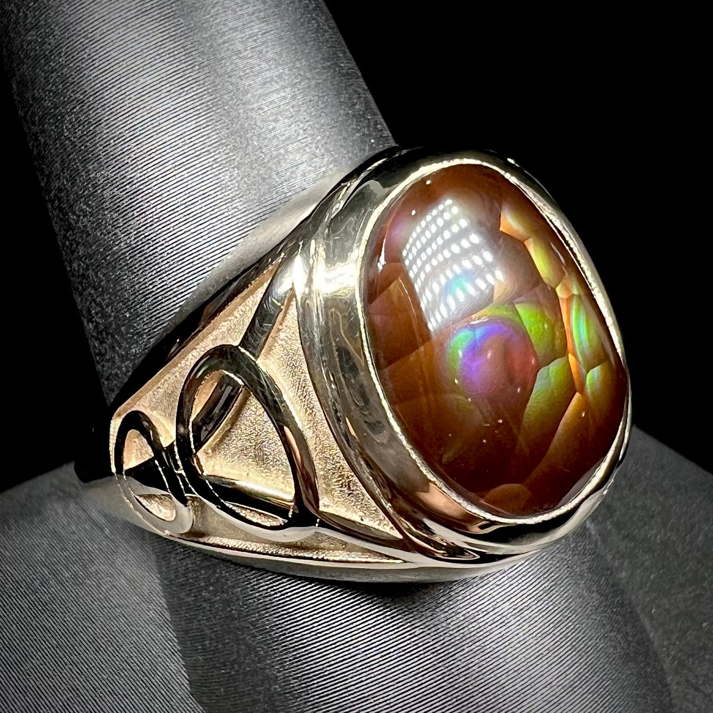 A men's solid yellow gold ring set with a Mexican fire agate stone.  The fire agate has a puple bull's eye pattern.