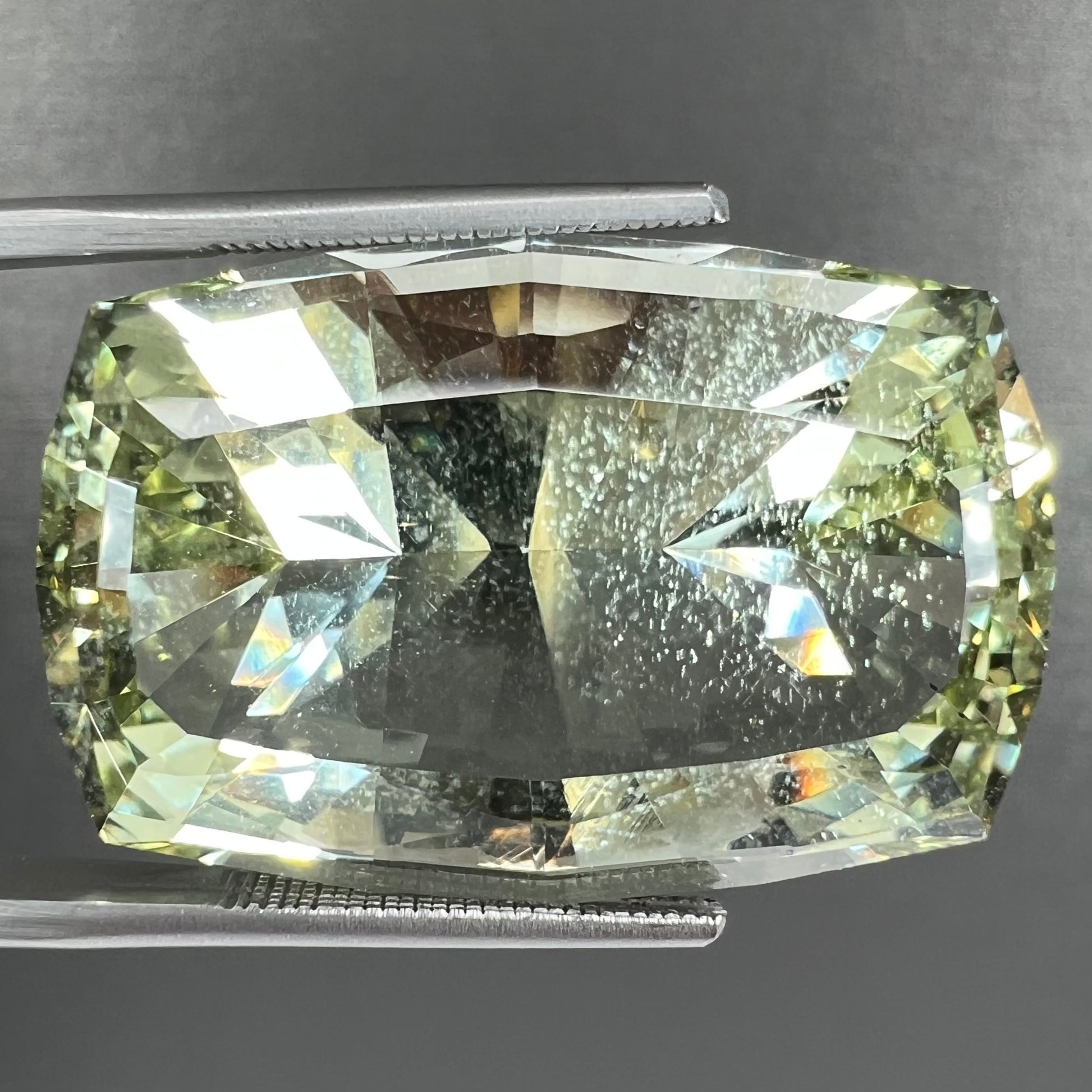A loose, modified cushion cut heliodor beryl gemstone.  The stone is a yellow-green color.