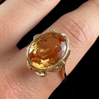 A ladies' yellow gold solitaire ring set with an 8.00 carat oval cut orange hessonite garnet.