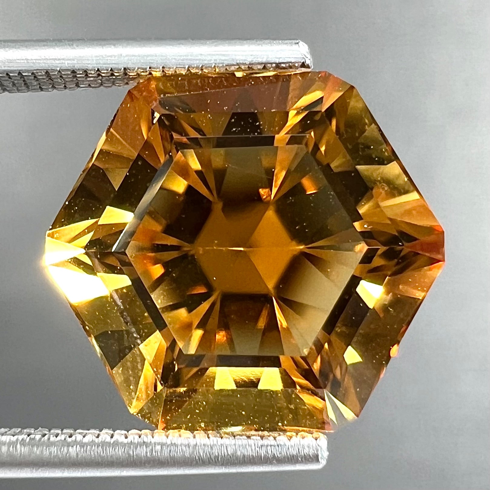 A loose, faceted hexagon cut citrine gem.  The stone is golden yellow color.