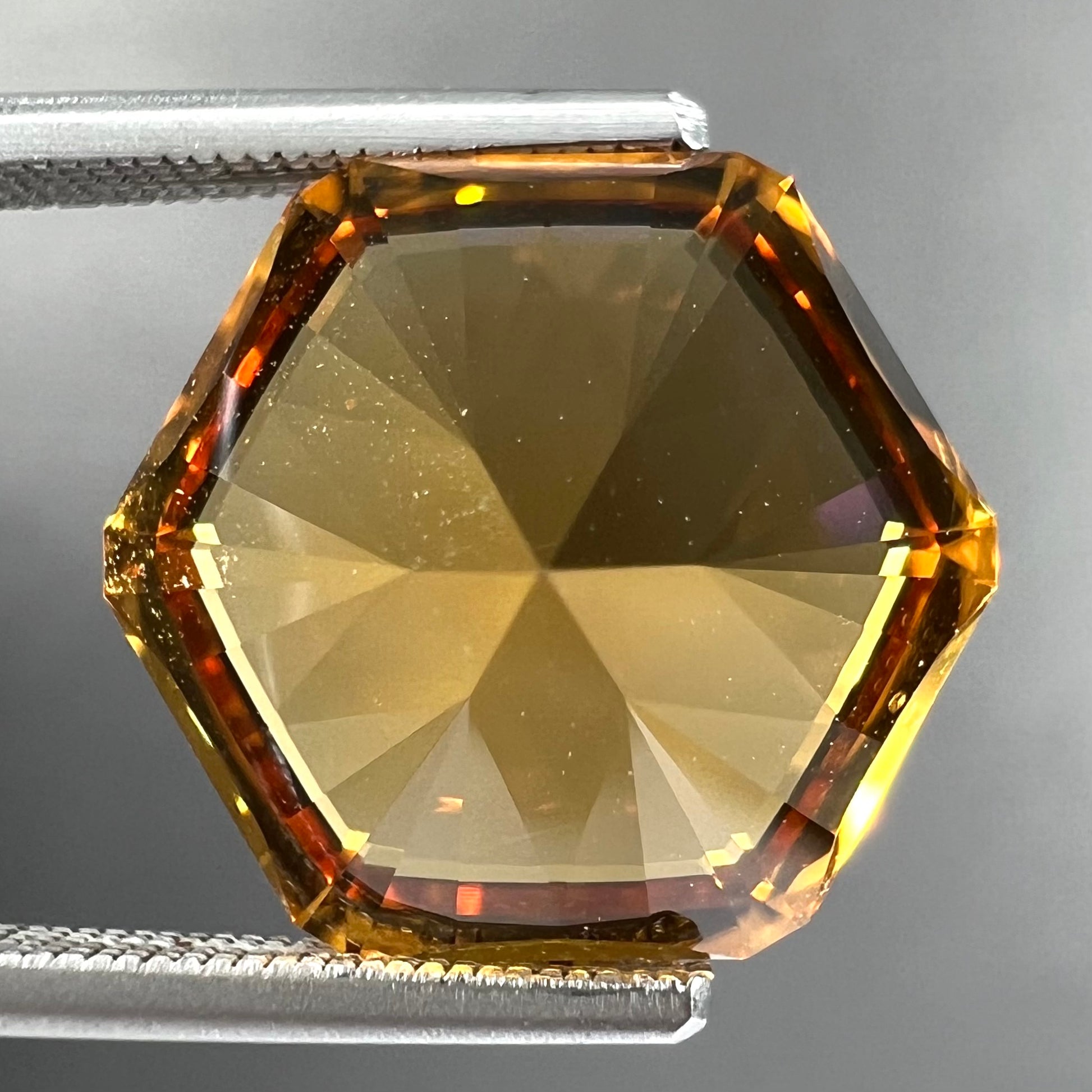 A loose, faceted hexagon cut citrine gem.  The stone is golden yellow color.