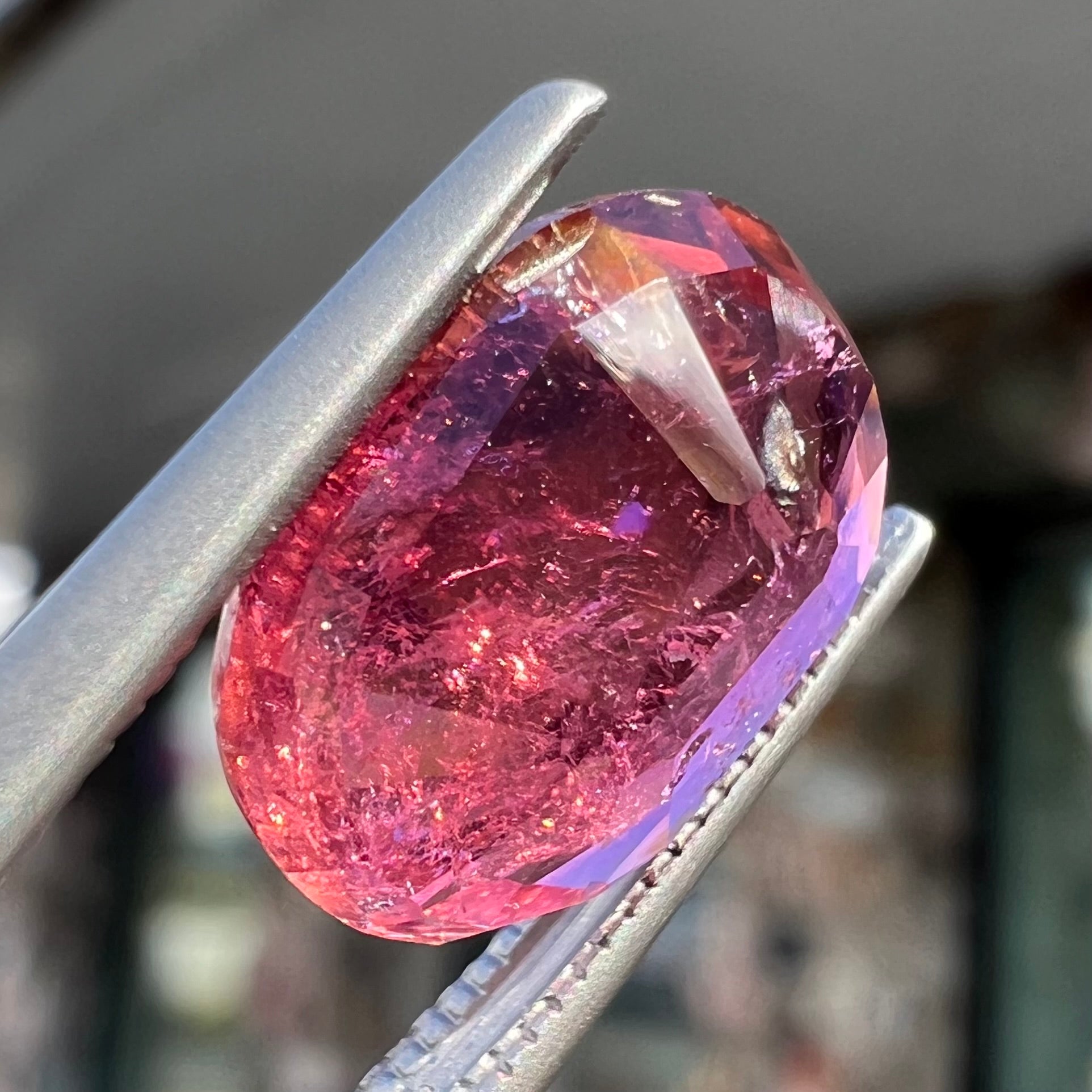 A faceted, oval cut, melon pink tourmaline gemstone.