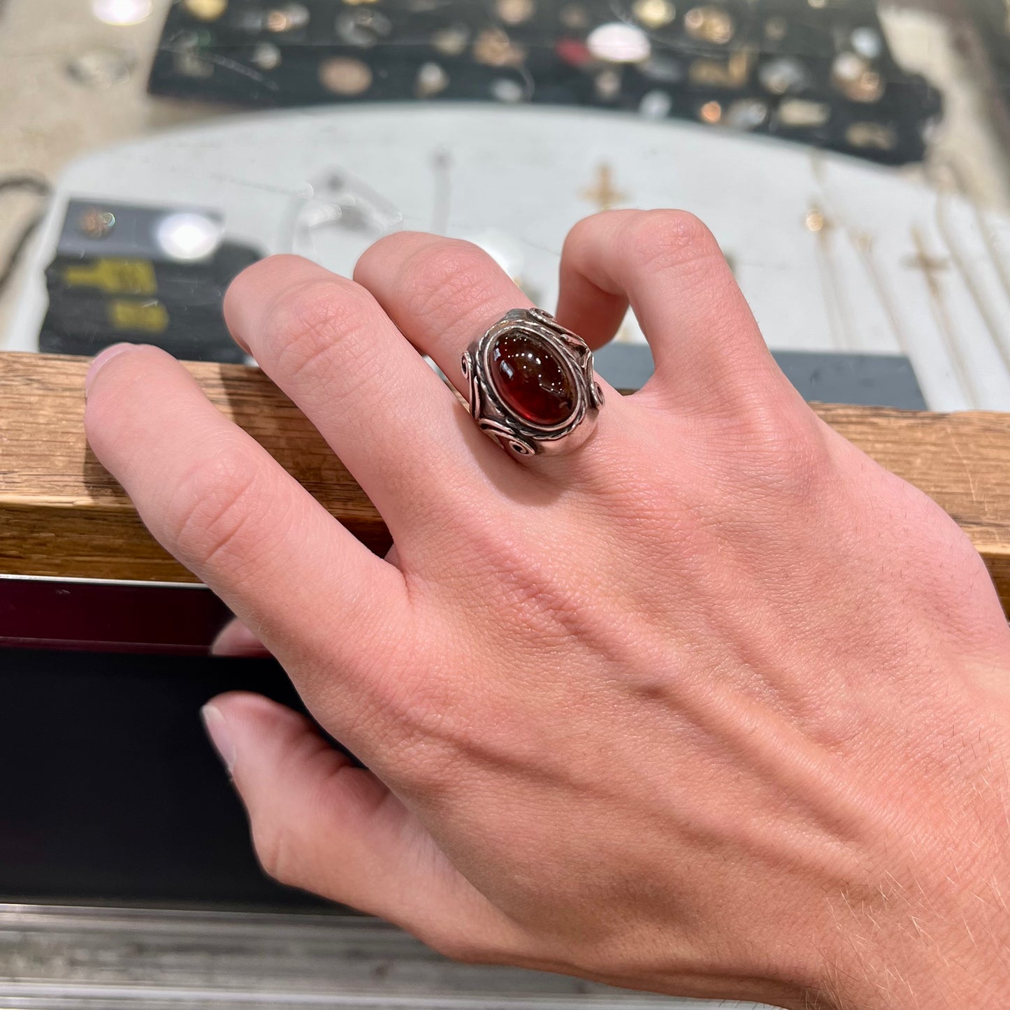 A sterling silver filigree style ring set with an oval cabochon cut red-orange amber stone.