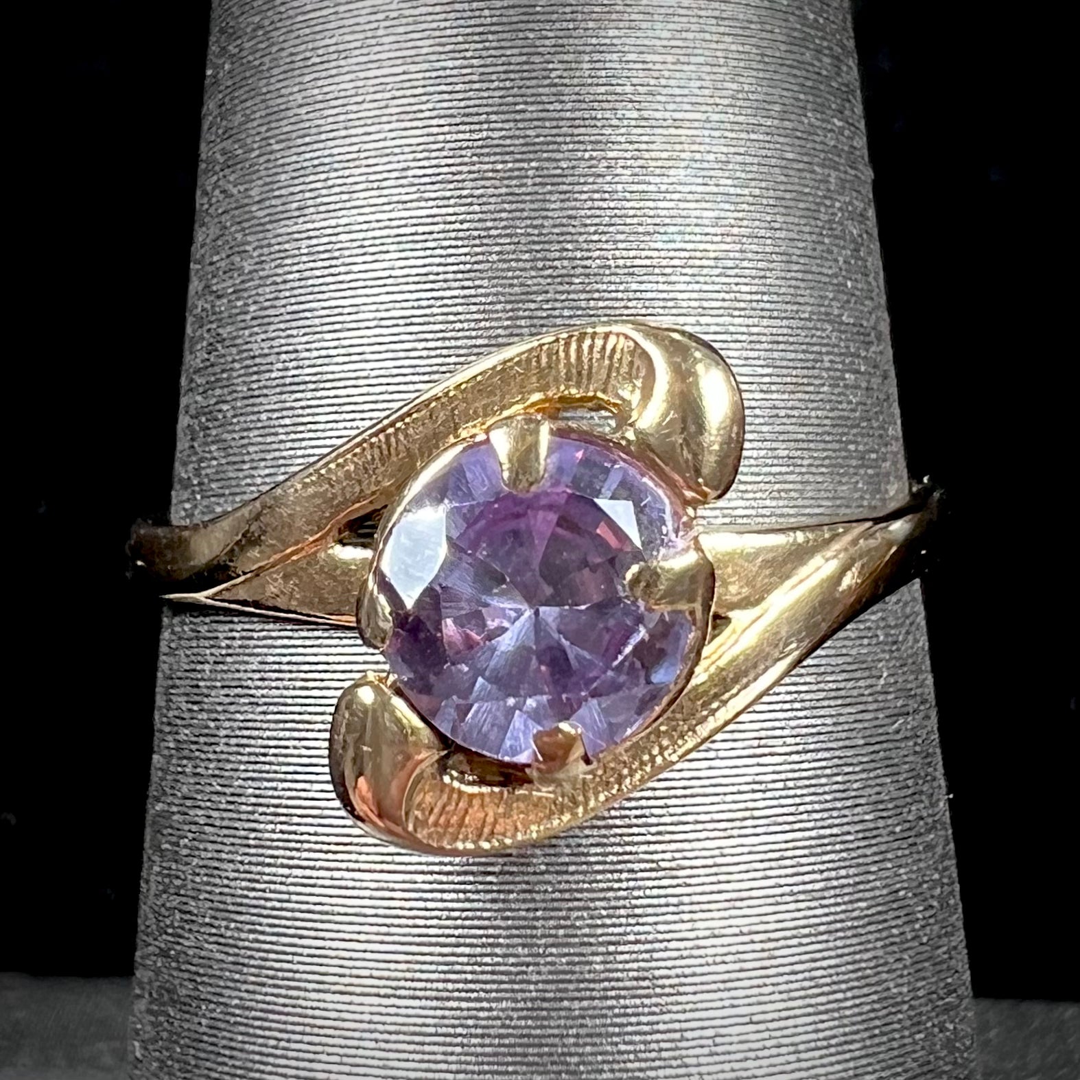 A vintage 1960's yellow gold ring set with a round synthetic purple alexandrite.  The prongs are worn.