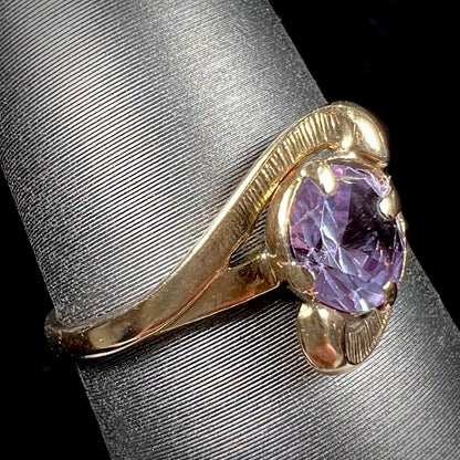 A vintage 1960's yellow gold ring set with a round synthetic purple alexandrite.  The prongs are worn.