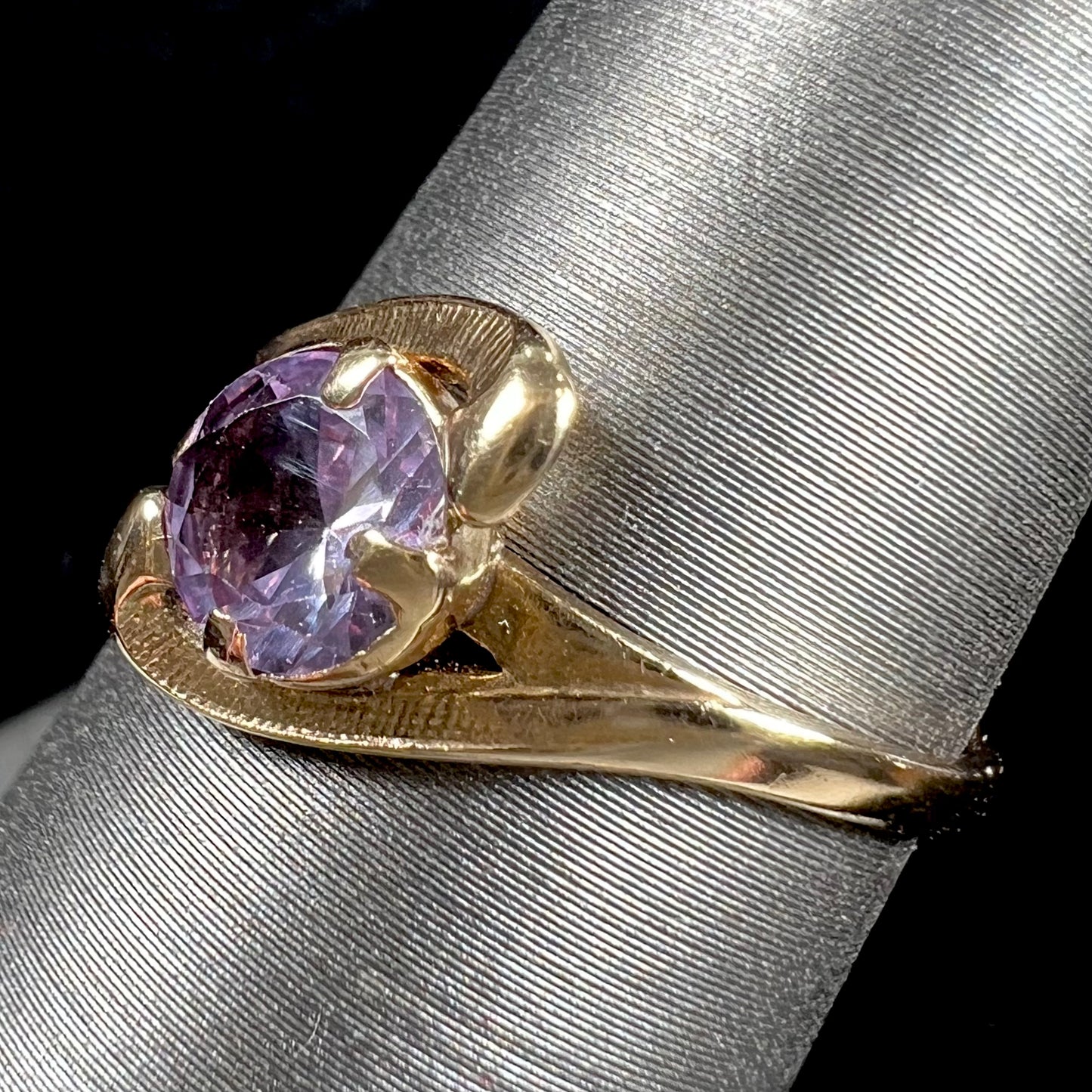 A vintage 1960's yellow gold ring set with a round synthetic purple alexandrite.  The prongs are worn.