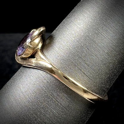 A vintage 1960's yellow gold ring set with a round synthetic purple alexandrite.  The prongs are worn.