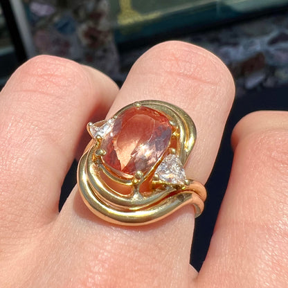 An 18 karat yellow gold ring set with two triangle cut diamonds and a cushion cut imperial topaz.