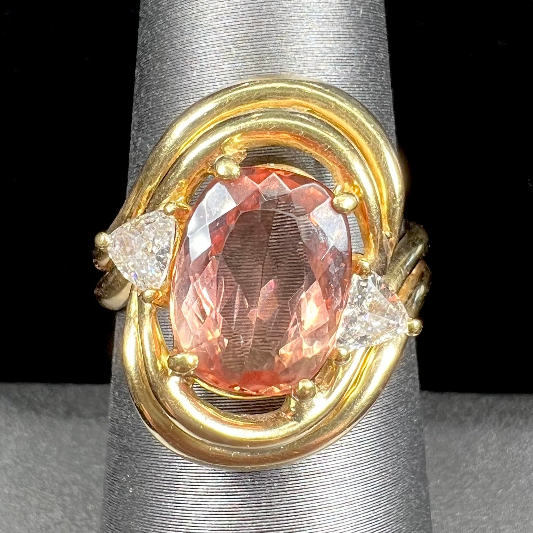 An 18 karat yellow gold ring set with two triangle cut diamonds and a cushion cut imperial topaz.