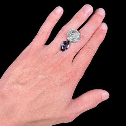 A loose, pear shaped bicolor iolite gemstone.  The stone shows violite purple and silver colors.