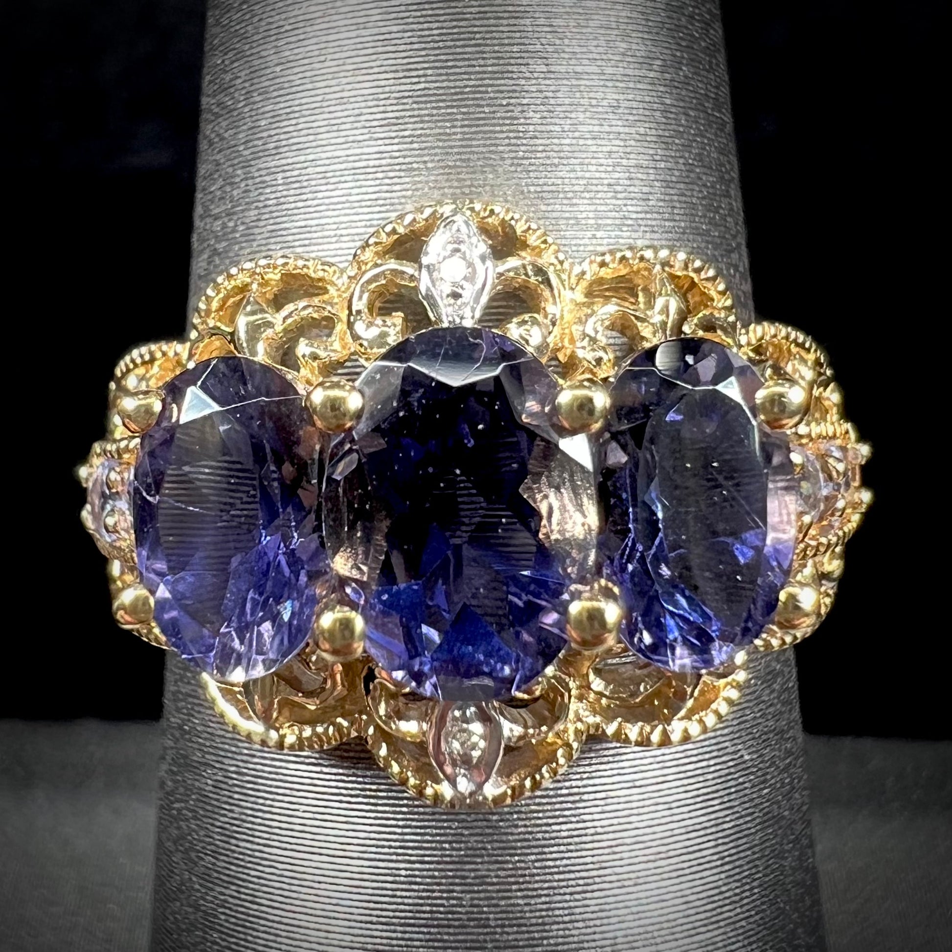 A ladies' three stone iolite ring in yellow gold set with diamond and B grade tanzanite accents.