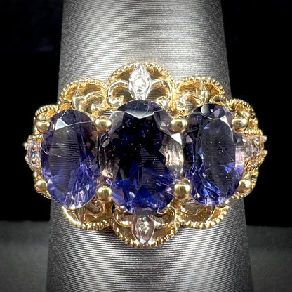 A ladies' three stone iolite ring in yellow gold set with diamond and B grade tanzanite accents.