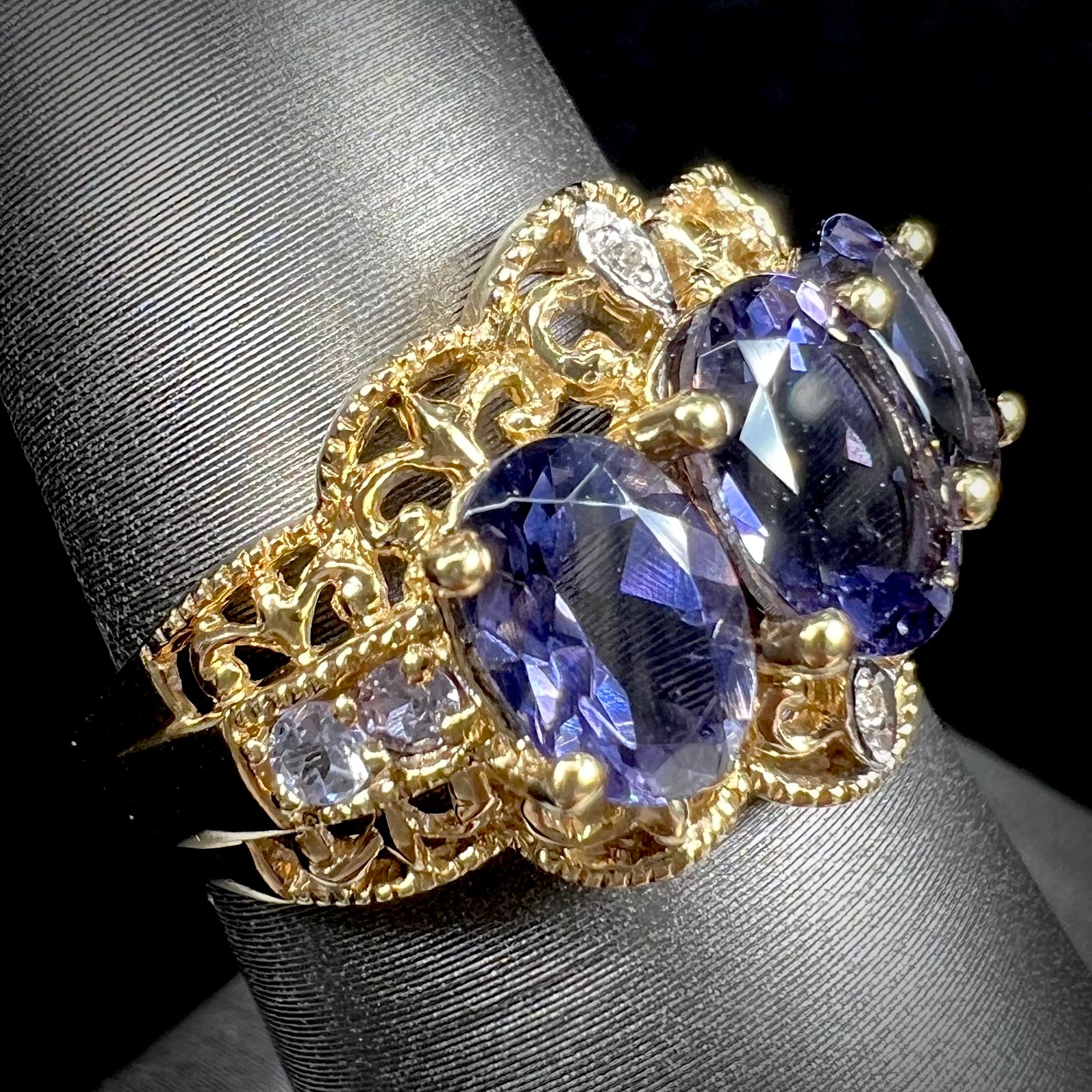 A ladies' three stone iolite ring in yellow gold set with diamond and B grade tanzanite accents.