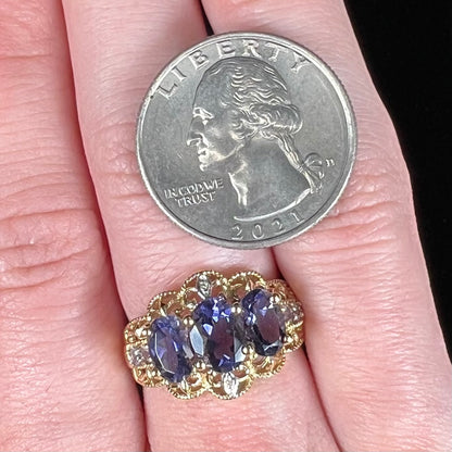 A ladies' three stone iolite ring in yellow gold set with diamond and B grade tanzanite accents.