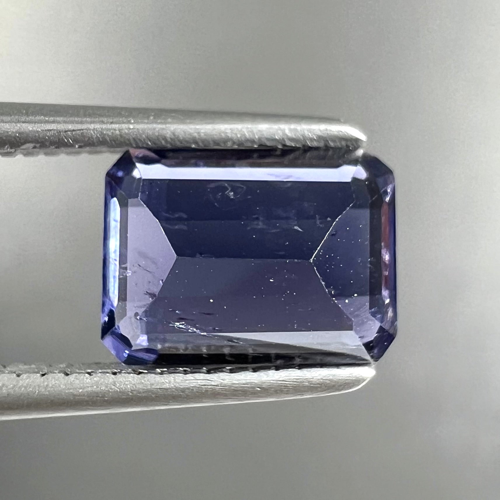 A loose, emerald cut blue iolite gemstone.