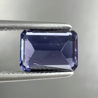 A loose, emerald cut blue iolite gemstone.