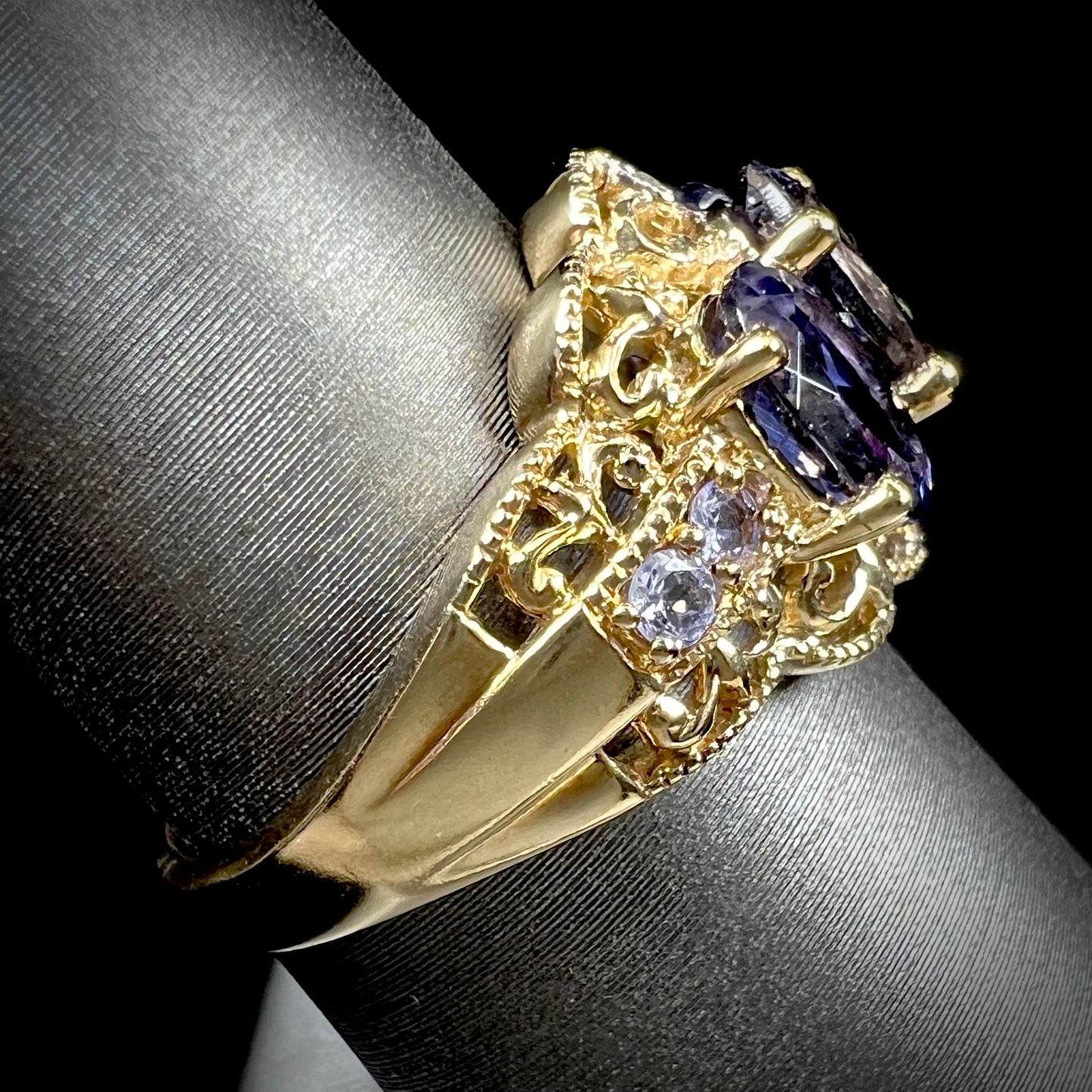 A ladies' three stone iolite ring in yellow gold set with diamond and B grade tanzanite accents.