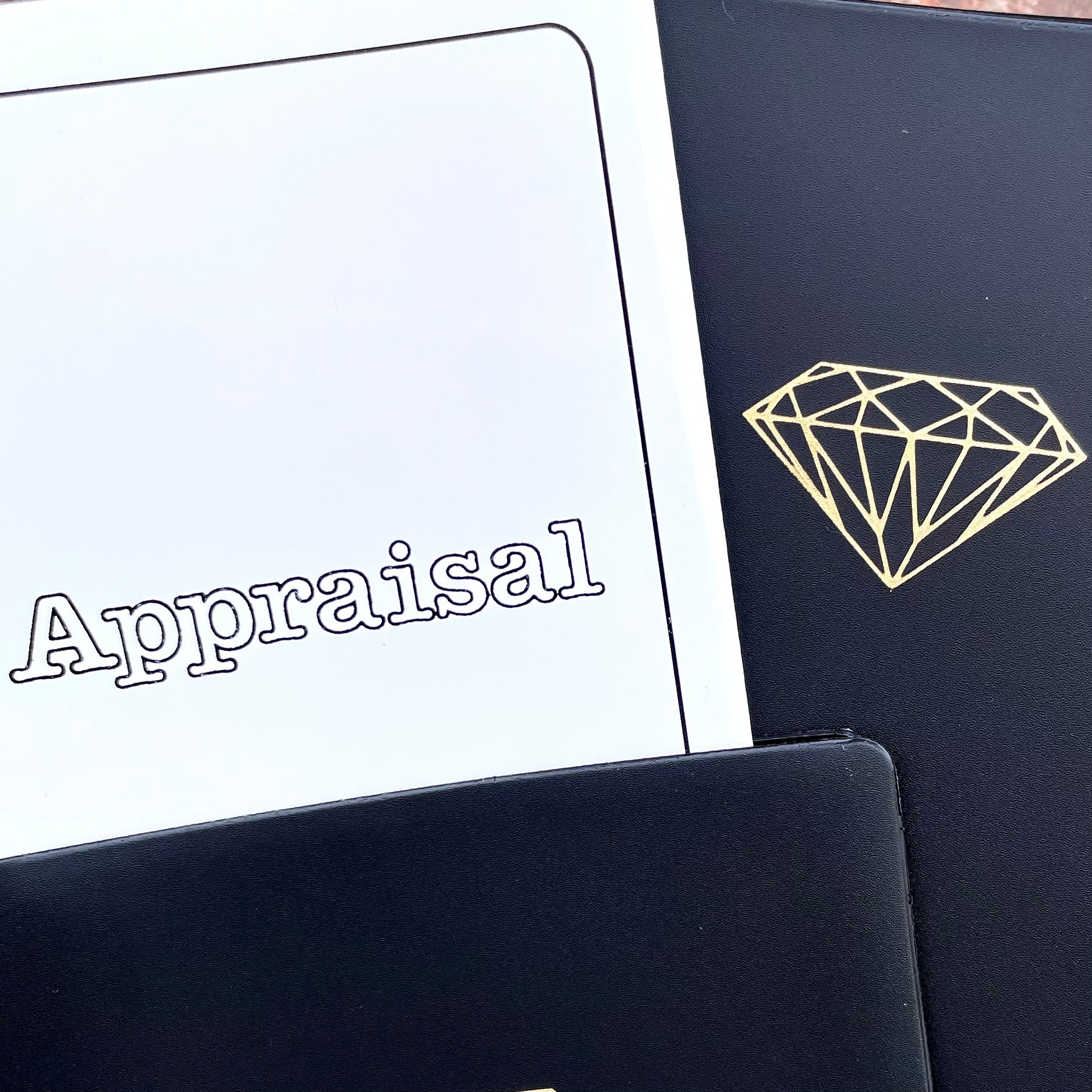 A black vinyl folder with the picture of a diamond on it next to a folded white paper sheet that reads "Appraisal."