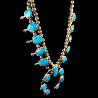 A vintage Navajo squash blossom necklace set with blue Kingman turquoise stones.