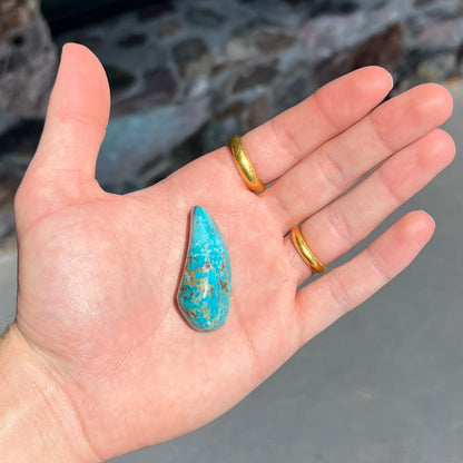 A loose, freeform cabochon cut Kingman turquoise stone from Arizona.  The stone is blue with gray and brown matrix.