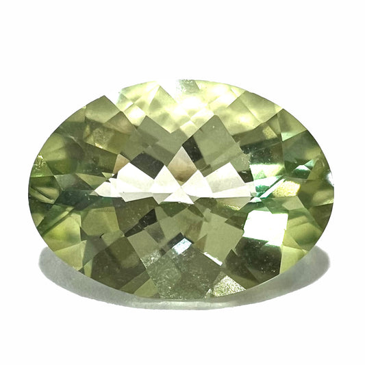 An oval checkerboard cut kiwi mystic topaz gemstone.  The stone is a light yellowish green color.